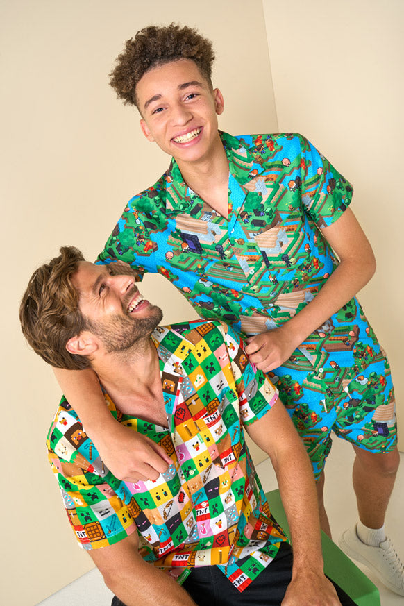 Two people wearing colorful Minecraft outfits with a playful design on a plain background