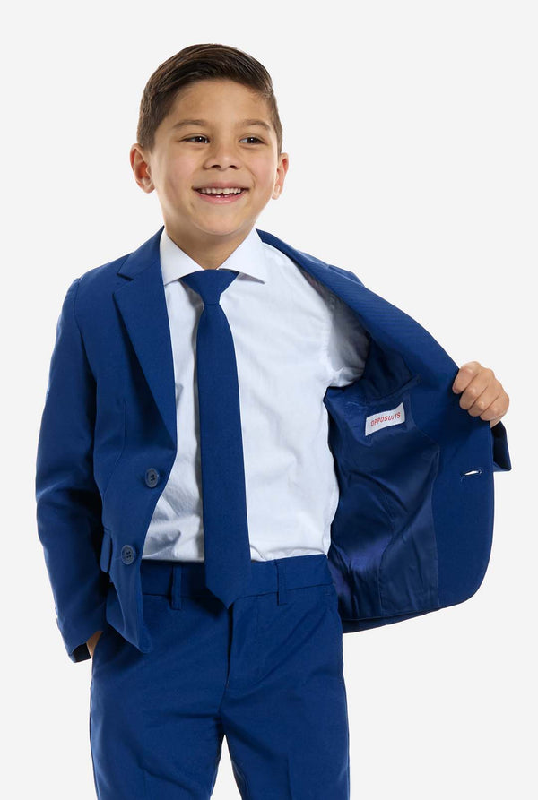 Young boy wearing a blue suit with a white shirt and blue tie on a white background