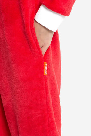 Close-up of the red Knuckles onesie's side pocket with visible orange Opposuits label. Child's hand is placed inside the pocket.