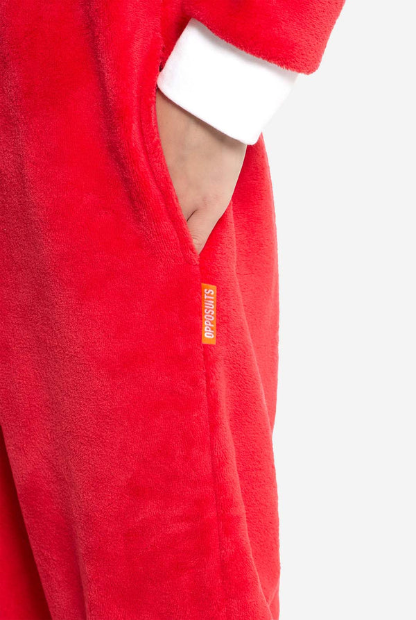 Close-up of the red Knuckles onesie's side pocket with visible orange Opposuits label. Child's hand is placed inside the pocket.