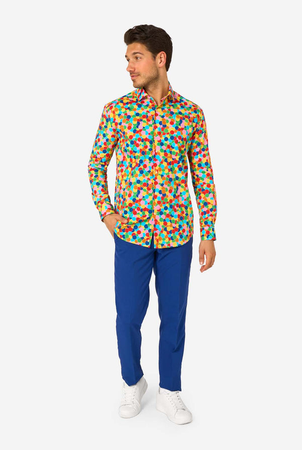 Man wearing a colorful confetti pattern shirt and blue pants on a white background
