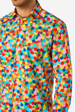 Person wearing a colorful polka dot confetti shirt with a plain background, close-up.