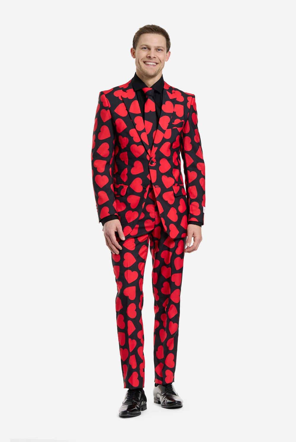 Man wearing a black suit with red heart patterns on a white background