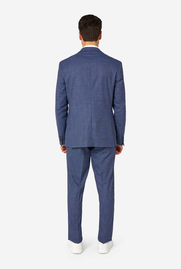 A men wearing a navy and blue checkered suit with a white dress shirt. The suit has a modern fit with two buttons and flap pockets. He stands against a plain white background. View from the back