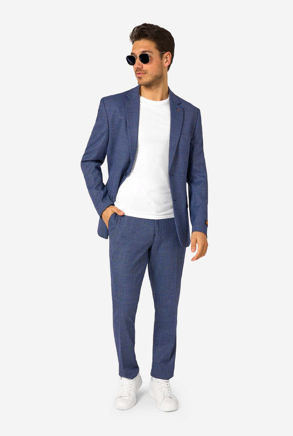 A men wearing a navy and blue checkered suit with a white dress shirt. The suit has a modern fit with two buttons and flap pockets. He stands against a plain white background. Full body image