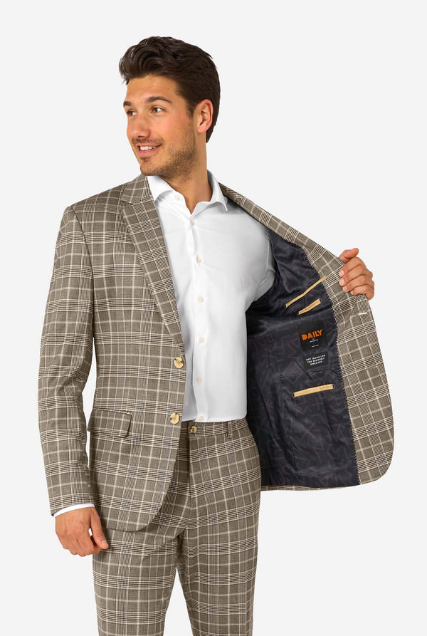 A men wearing a tan checkered suit with a white dress shirt. The suit has a modern fit with two buttons and flap pockets. He stands against a plain white background. Holding his jacket open