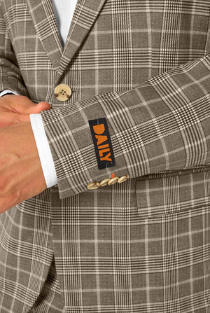 A men wearing a tan checkered suit with a white dress shirt. The suit has a modern fit with two buttons and flap pockets. He stands against a plain white background. Close up of the sleeves