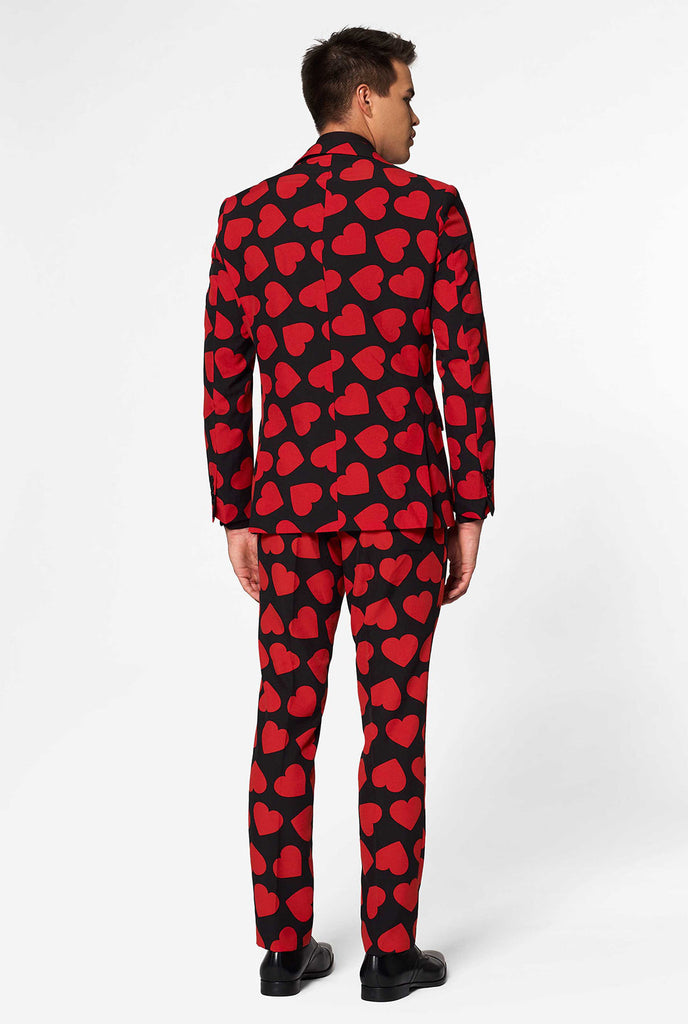Man wearing black suit with red hearts print