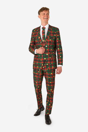 Man in a red and green tartan plaid suit with gold star and dot accents, smiling while standing with one hand near his jacket button.