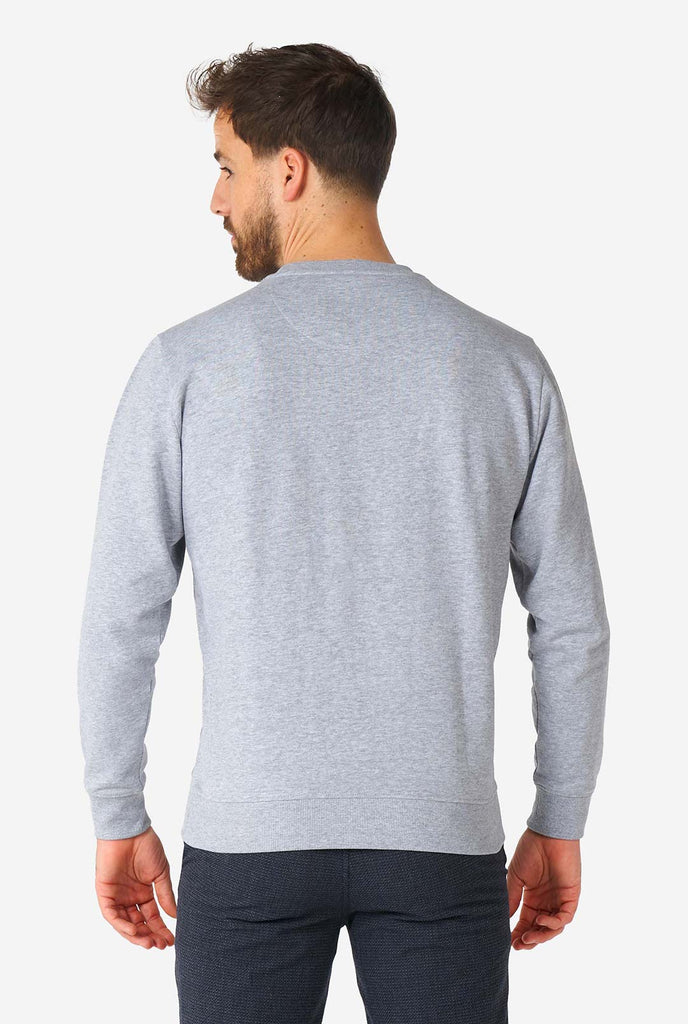 Man wearing grey sweater with chenille rock, paper, scissors embroidery