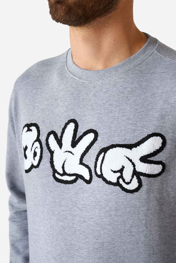 Man wearing grey sweater with chenille rock, paper, scissors embroidery