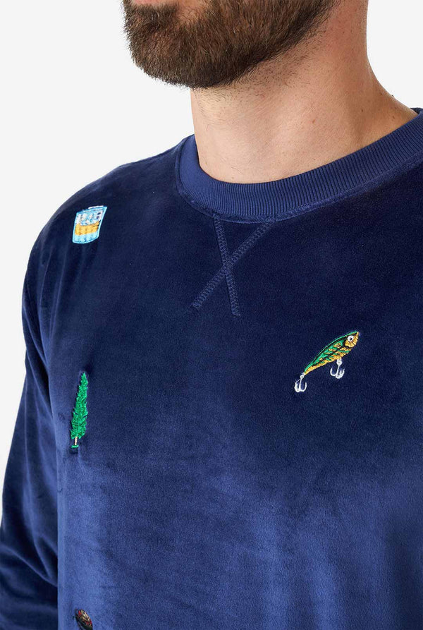 Man wearing velvet blue Christmas sweater with Christmas icons