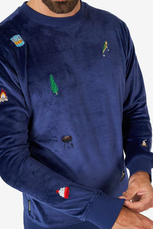 Man wearing velvet blue Christmas sweater with Christmas icons