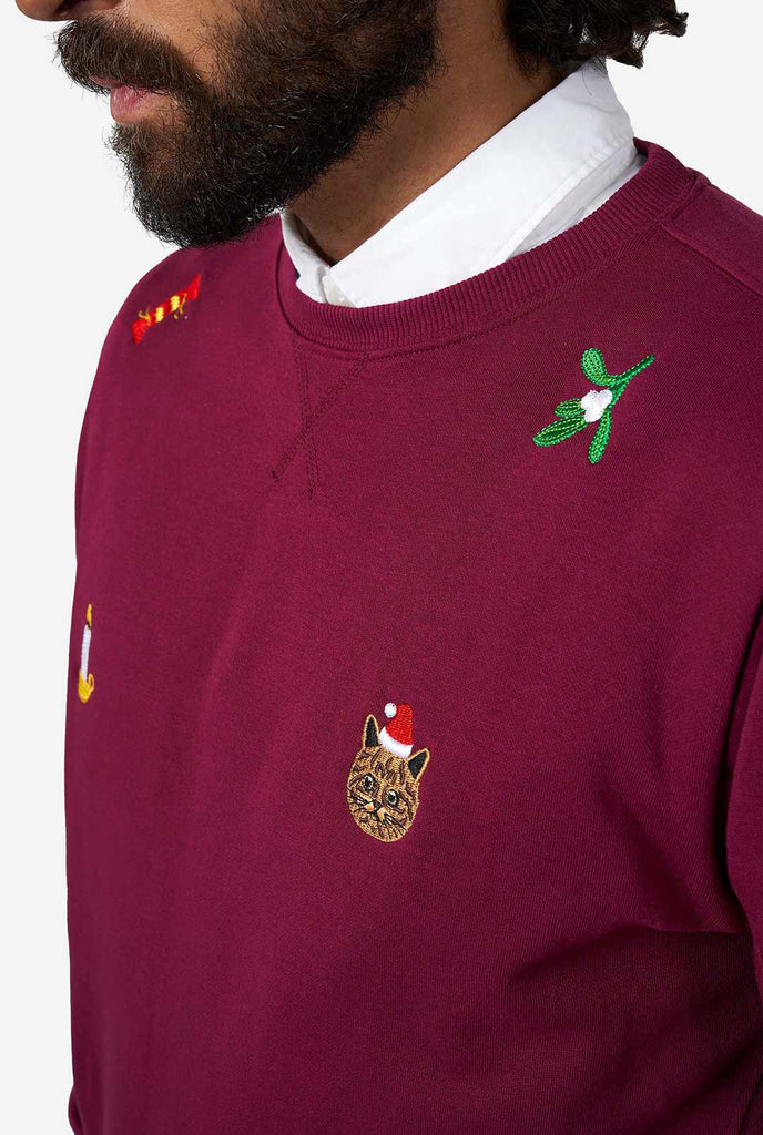 Man wearing burgundy red Christmas sweater with Christmas icons