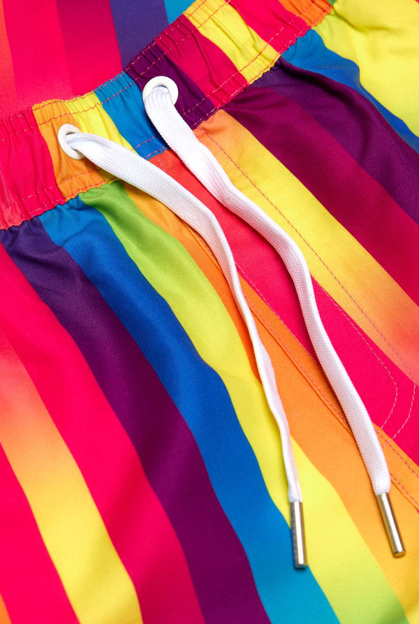 Image of a vertically striped rainbow-colored summer set, consisting of shirt and shorts. Close up of the shorts. 
