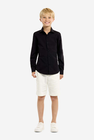 Young boy wearing a black shirt and white shorts on a white background