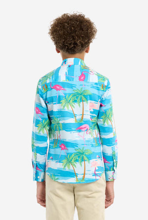 Child wearing a colorful shirt with palm tree and flamingo pattern on a white background