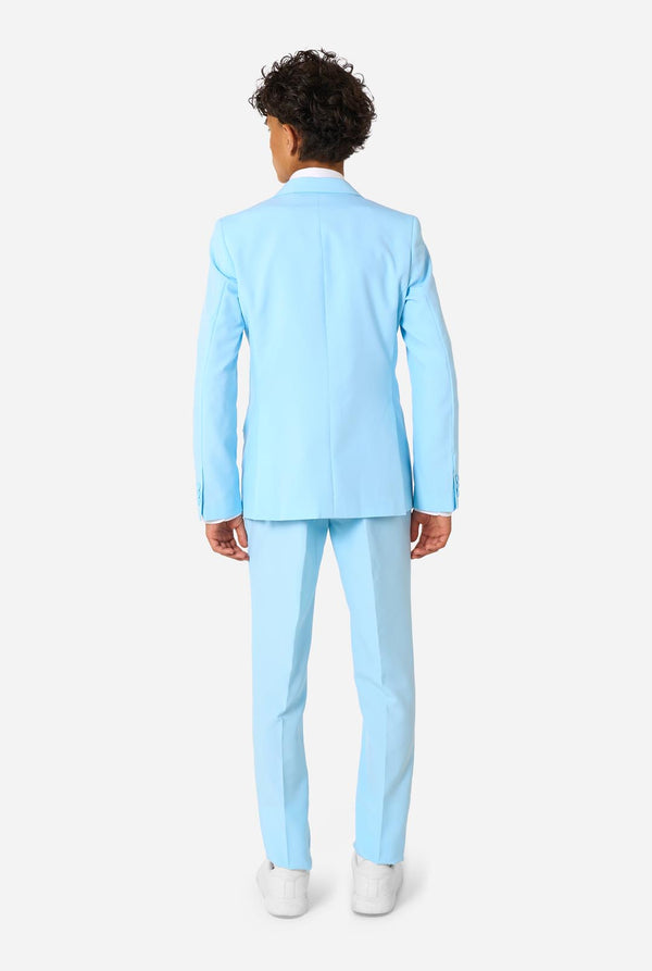 Teen wearing a light blue suit with a white shirt and tie on a light background. View from the back.