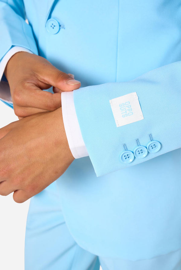 Teen wearing a light blue suit with a white shirt and tie on a light background. Sleeve close up.