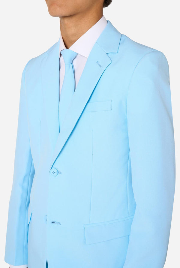 Teen wearing a light blue suit with a white shirt and tie on a light background. Chest close up.