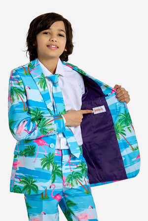 Child wearing a colorful suit with palm tree and flamingo pattern, pointing to the pocket.
