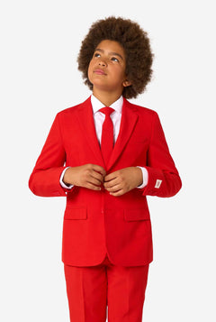 Child wearing a red suit with a white shirt and red tie on a white background