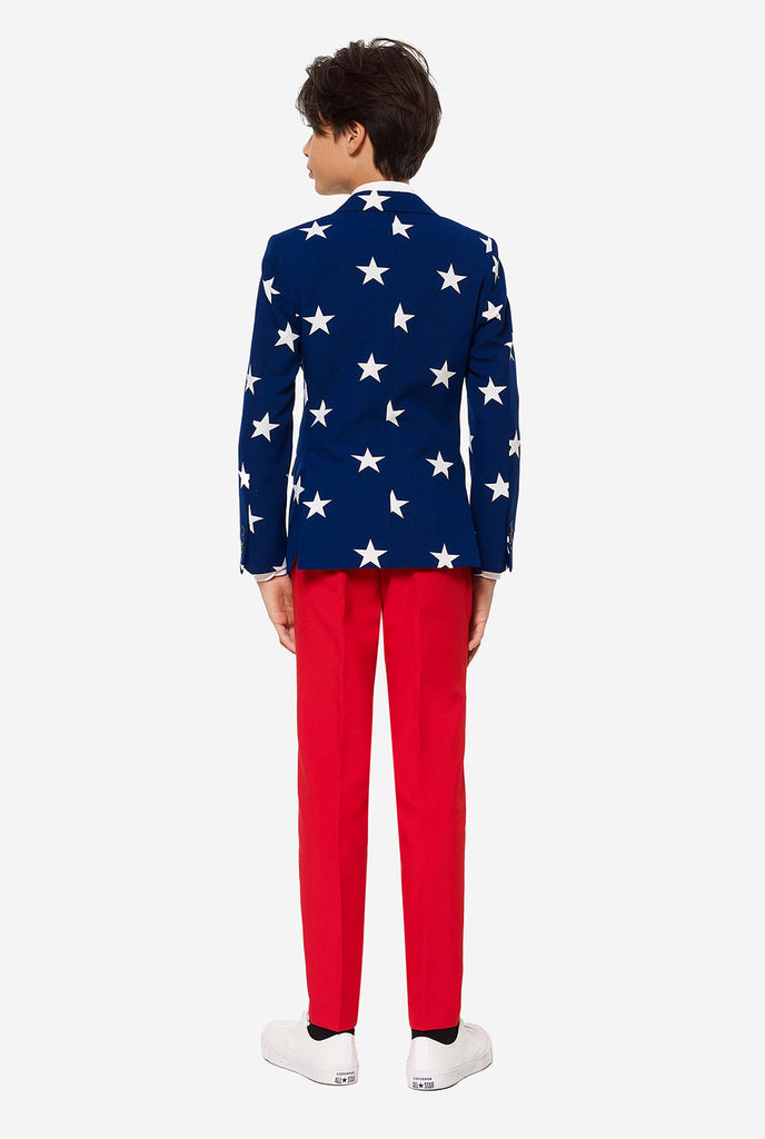 Teen wearing formal USA themed fourth of July suit, consisting of blue jacket and red pants. 