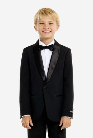 Young boy wearing a black tuxedo with a white shirt and black bow tie on a white background