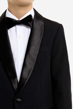 Black tuxedo with white shirt and black bow tie on a plain background