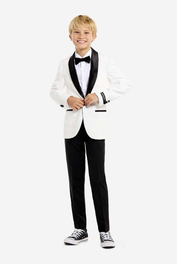Child wearing a formal white tuxedo with black lapels and pants on a white background