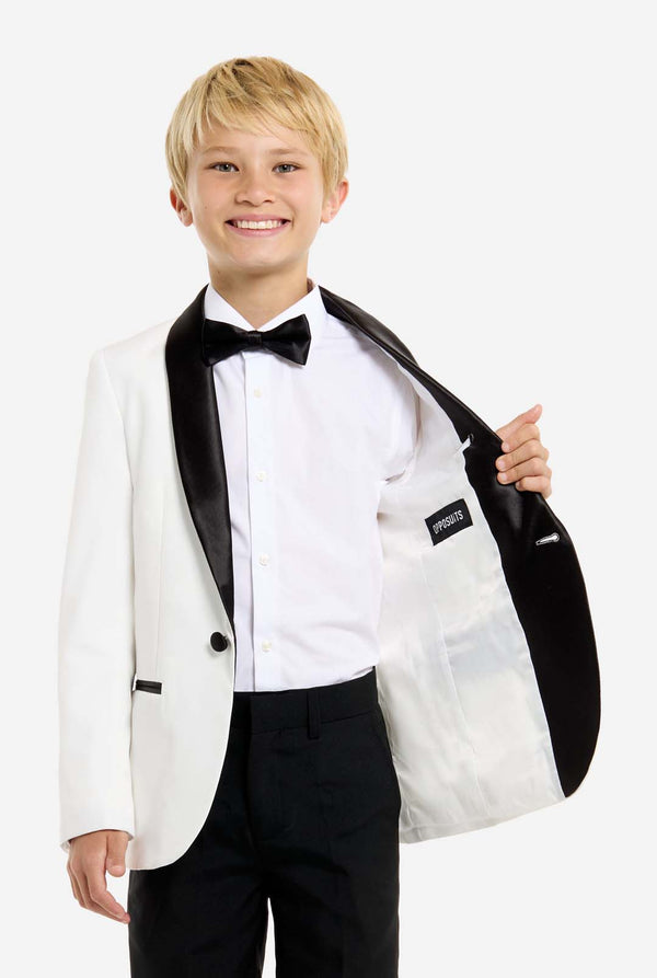 Young boy wearing a white tuxedo with black lapels and bow tie on a white background