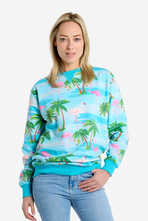 Woman wearing a tropical-themed sweatshirt with palm trees and flamingos on a white background
