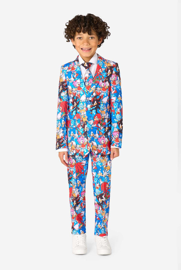 Young boy wearing a vibrant Sonic teen suit featuring colorful prints of Sonic the Hedgehog characters including Sonic, Knuckles, Tails, and Amy, paired with a matching tie and white shirt. Full body image.