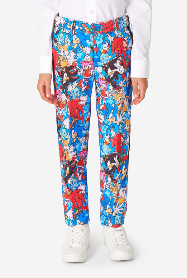 Young boy wearing a vibrant Sonic teen suit featuring colorful prints of Sonic the Hedgehog characters including Sonic, Knuckles, Tails, and Amy, paired with a matching tie and white shirt. Close-up pants.