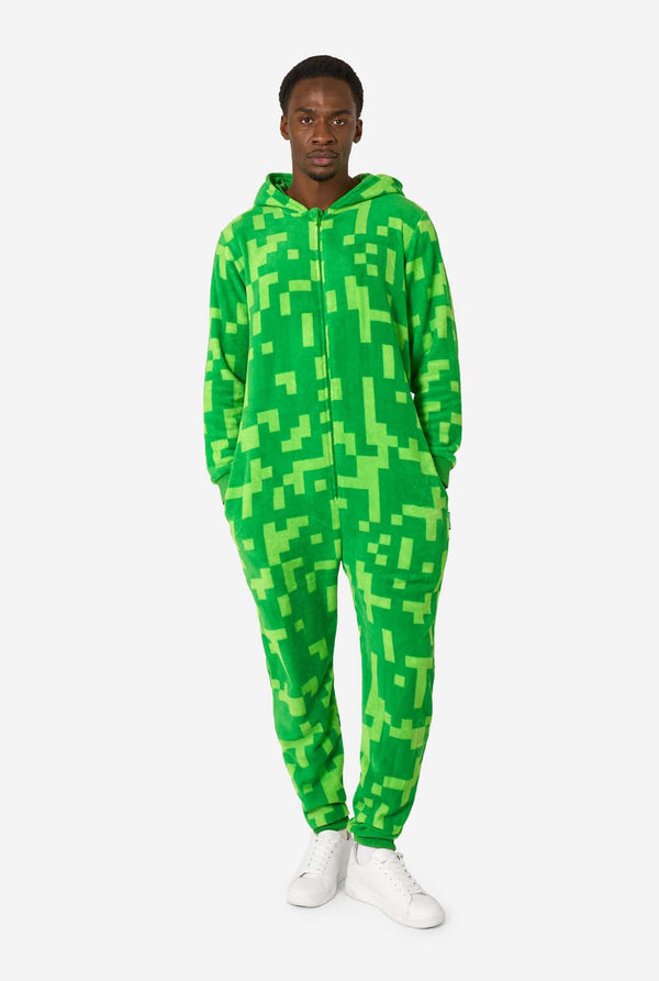 A man wearing green pixelated onesie designed to look like the Minecraft Creeper character. The onesie has a hood with the Creeper’s iconic black pixel face. The man has the hood on his back and is looking into the camera, full body image.