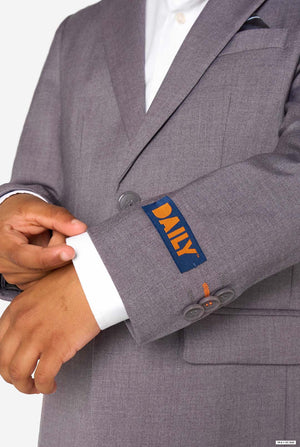 Gray suit jacket with 'DAILY' logo on sleeve, worn by a person.