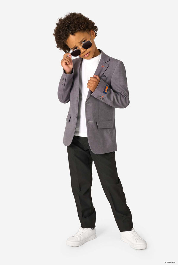 Child wearing a gray blazer, black pants, and white sneakers on a white background