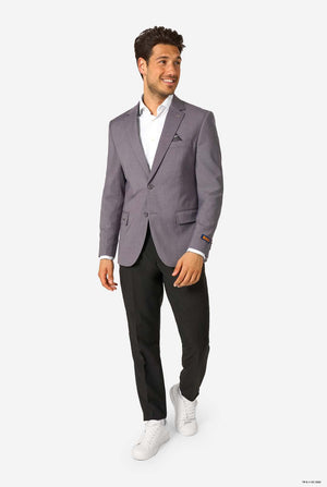 Man wearing a gray blazer, white shirt, black pants, and white sneakers on a grey background