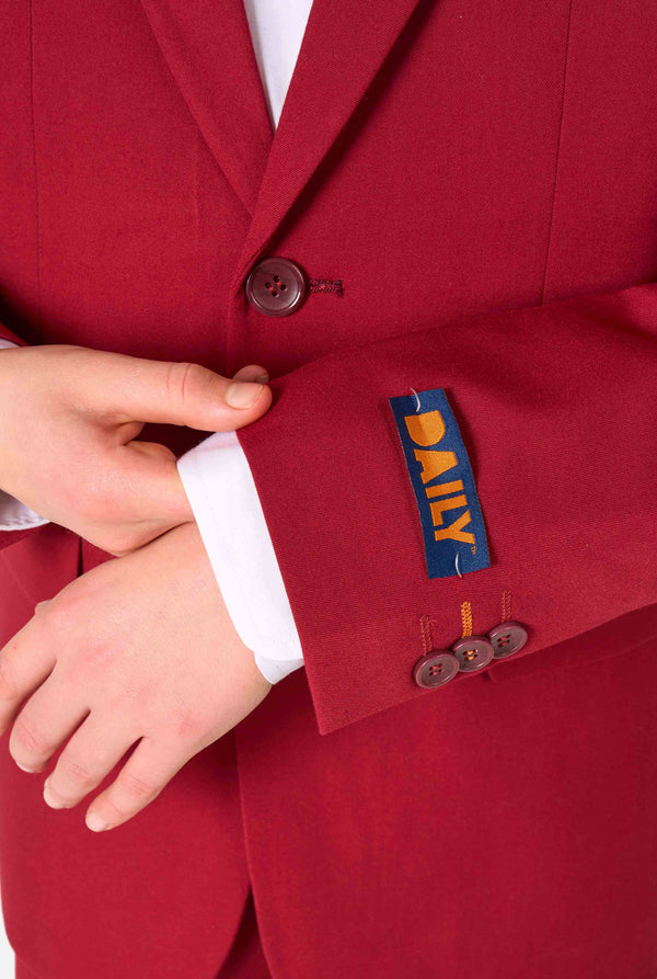 Teen boy wearing a stylish burgundy red suit with a white dress shirt, looking confidently. Perfect formal outfit for boys' special occasions, weddings, and parties. Sleeve close-up.