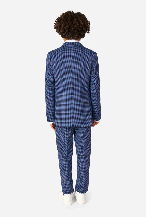 A boy wearing a navy and blue checkered suit with a white dress shirt. The suit has a modern fit with two buttons and flap pockets. He stands against a plain white background. View from the back.