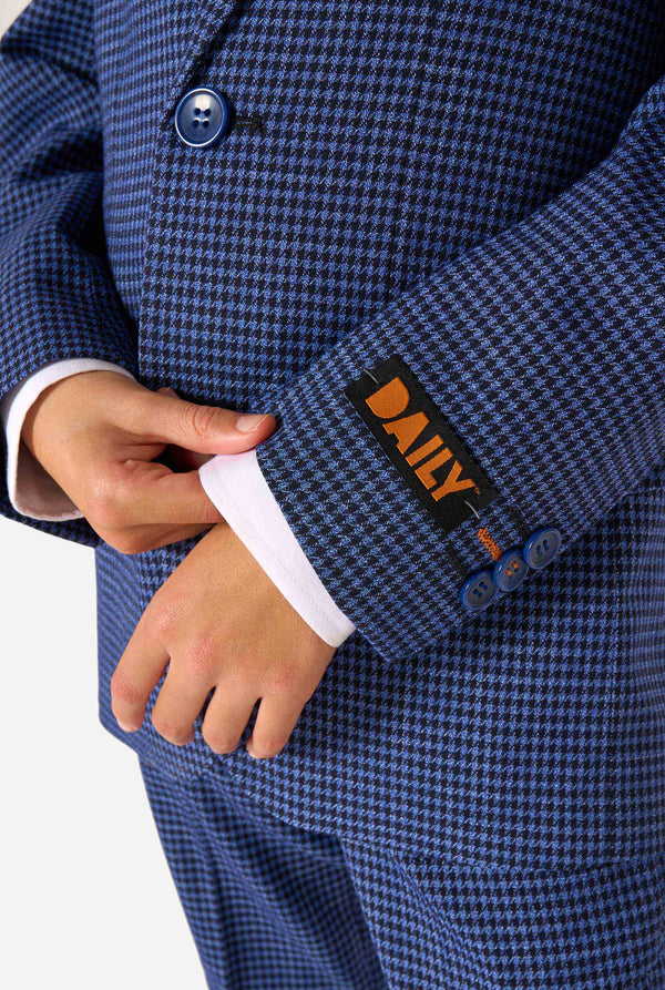 A boy wearing a navy and blue checkered suit with a white dress shirt. The suit has a modern fit with two buttons and flap pockets. He stands against a plain white background. Close up of the sleeves.