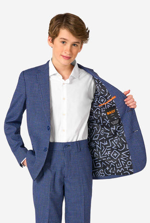 A young boy stands smiling while wearing a formal navy plaid suit jacket over a white button-down shirt. The suit features a subtle check pattern. Showing the inside of the jacket