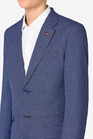 A young boy stands smiling while wearing a formal navy plaid suit jacket over a white button-down shirt. The suit features a subtle check pattern. Close up of the chest