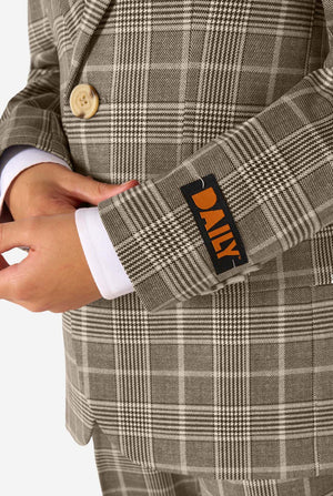 A boy wearing a tan checkered suit with a white dress shirt. The suit has a modern fit with two buttons and flap pockets. He stands against a plain white background. Close up of the sleeves.