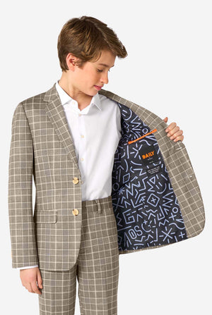 A young boy stands smiling while wearing a formal tan and beige plaid suit jacket over a white button-down shirt. The suit features a subtle check pattern. Showing the inside of the jacket