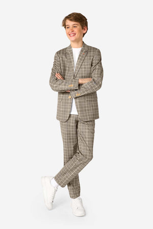 A young boy stands smiling while wearing a formal tan and beige plaid suit jacket over a white button-down shirt. The suit features a subtle check pattern. Full body image