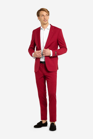 Image with light grey background and man wearing Bright Burgundy men’s suit and white shirt. Suits consists of blazer and pants. Full body image.