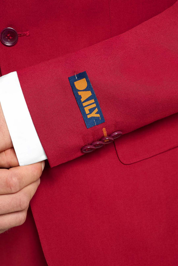 Image with light grey background and man wearing Bright Burgundy men’s suit and white shirt. Suits consists of blazer and pants. Focused on the sleeves.