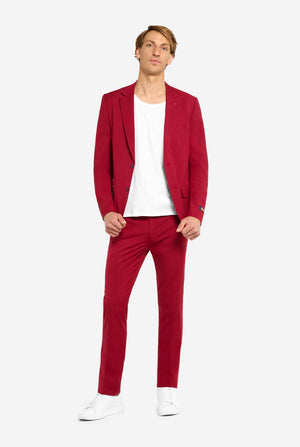 Image with light grey background and man wearing Bright Burgundy men’s suit and white shirt. Suits consists of blazer and pants. Man looking in the camera, full body image.