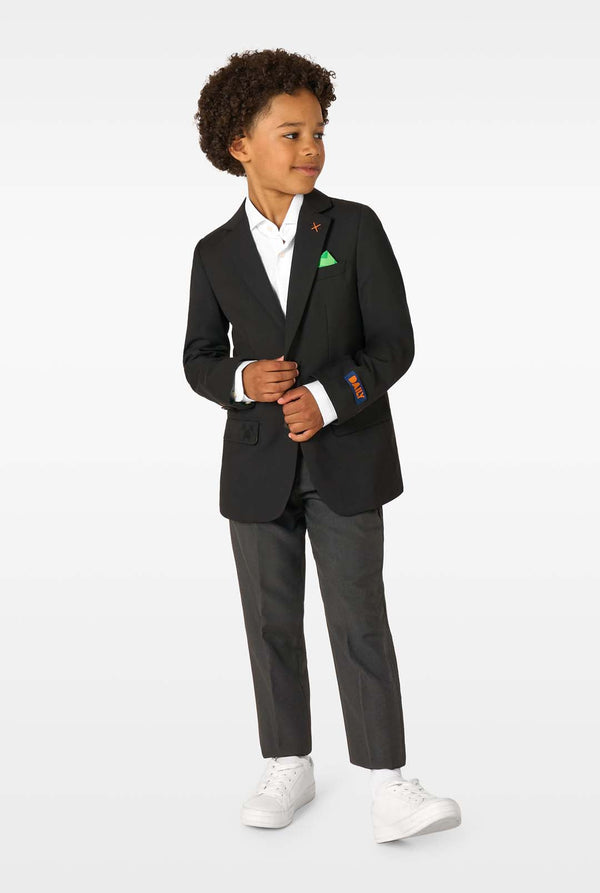 Child wearing a black suit with white shirt and sneakers on a white background